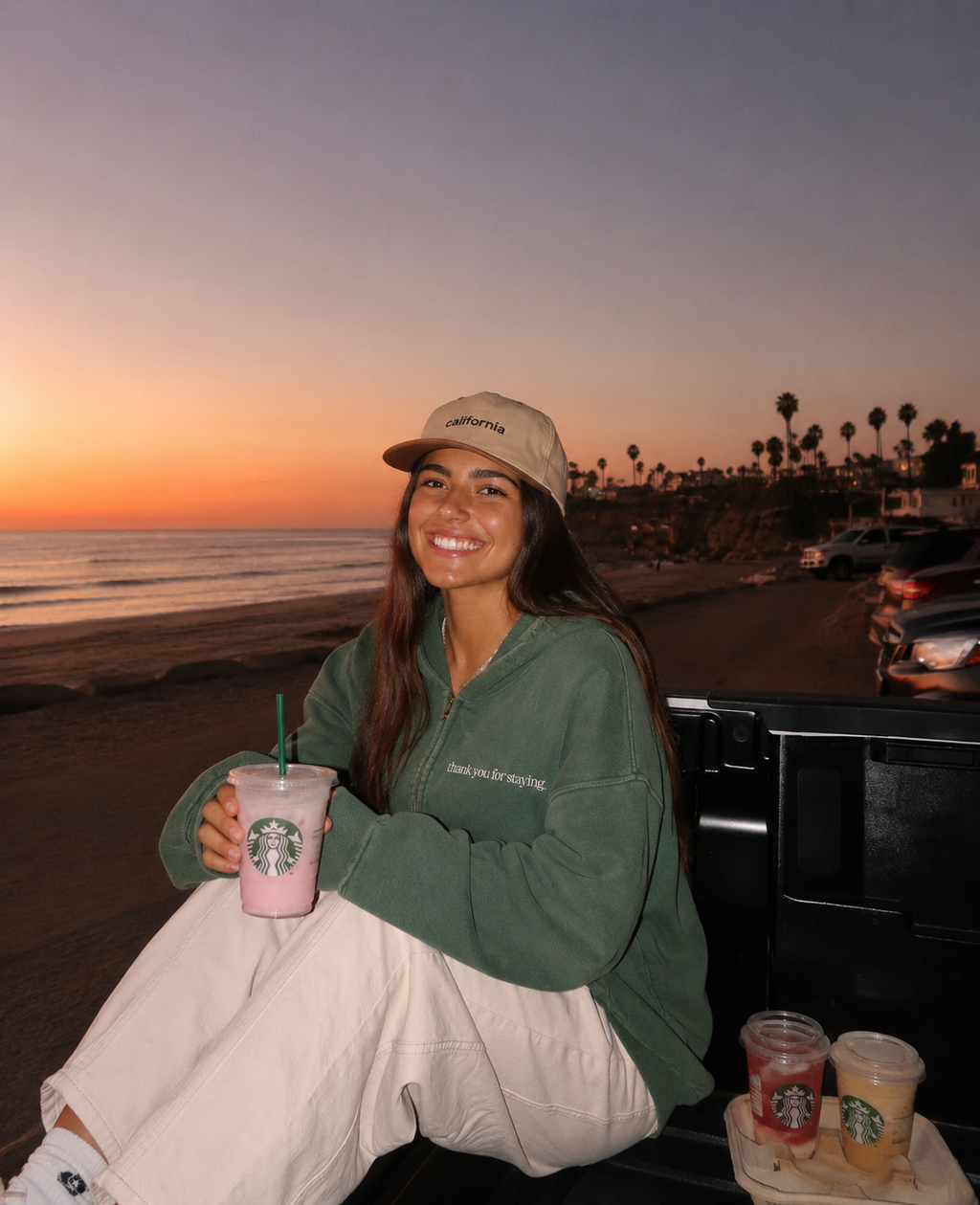 Woman wearing Thank You For Staying oversized zip hoodie at a California beach sunset