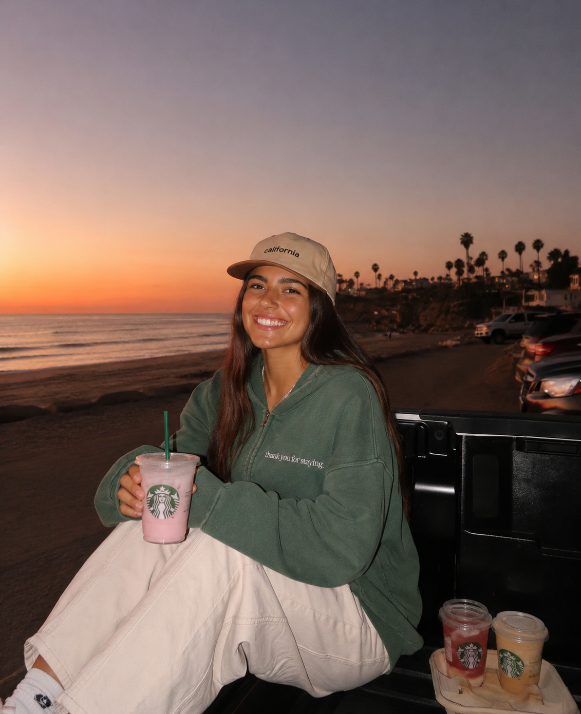 Woman wearing Thank You For Staying oversized zip hoodie at a California beach sunset